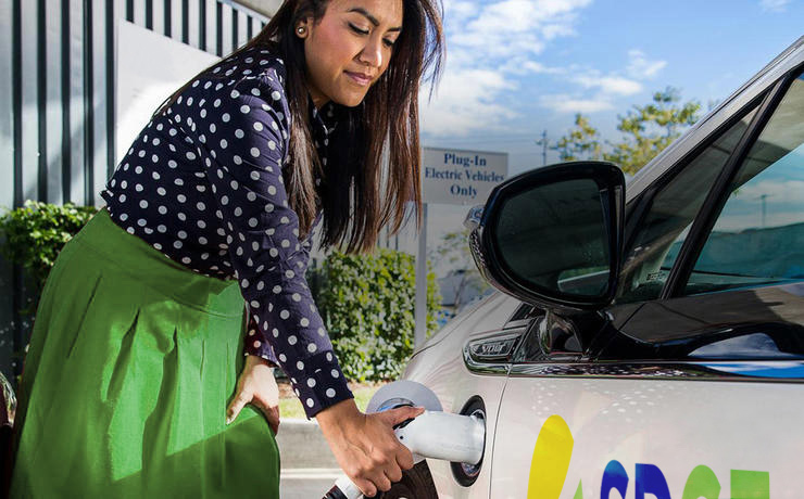 Woman charging an electric car, also known as an (EV) electric vehicle