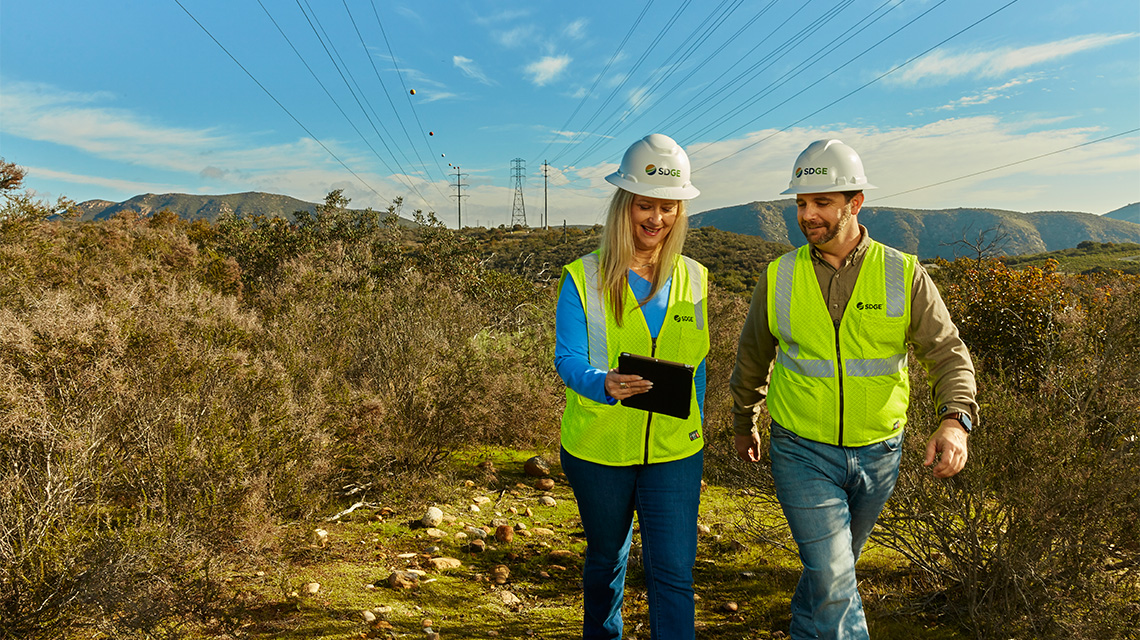 Two SDG&E workers walking by power lines