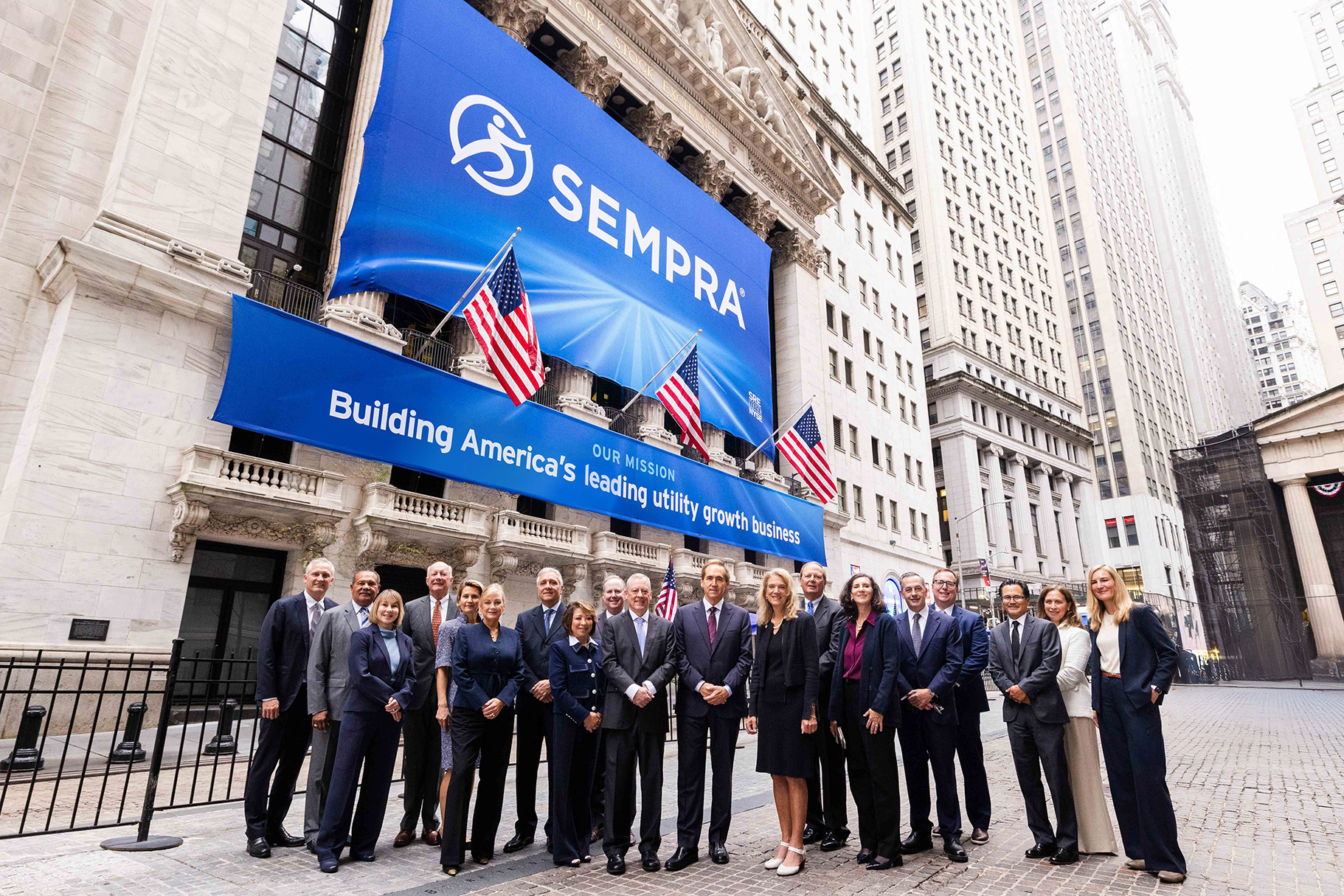 Jeffrey W. Martin, Chairman and CEO of Sempra with Sempra's leadership team in front of the New York Stock Exchange with Sempra's logo on a banner