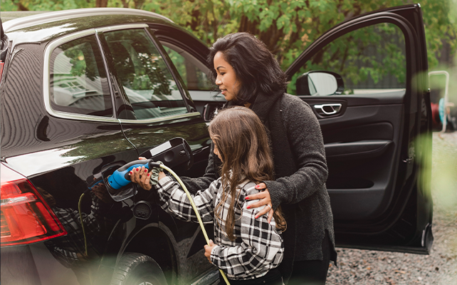 A mother and child charging their electric vehicle at an EV station